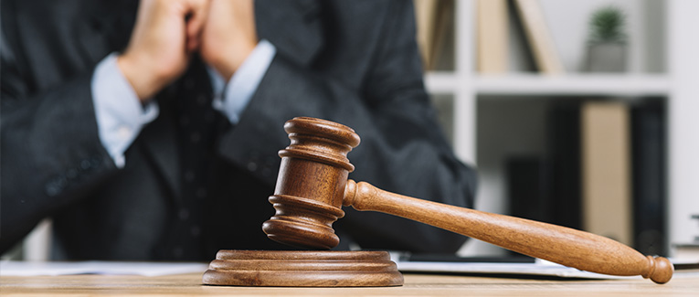 wood gavel with attorney or judge behind it