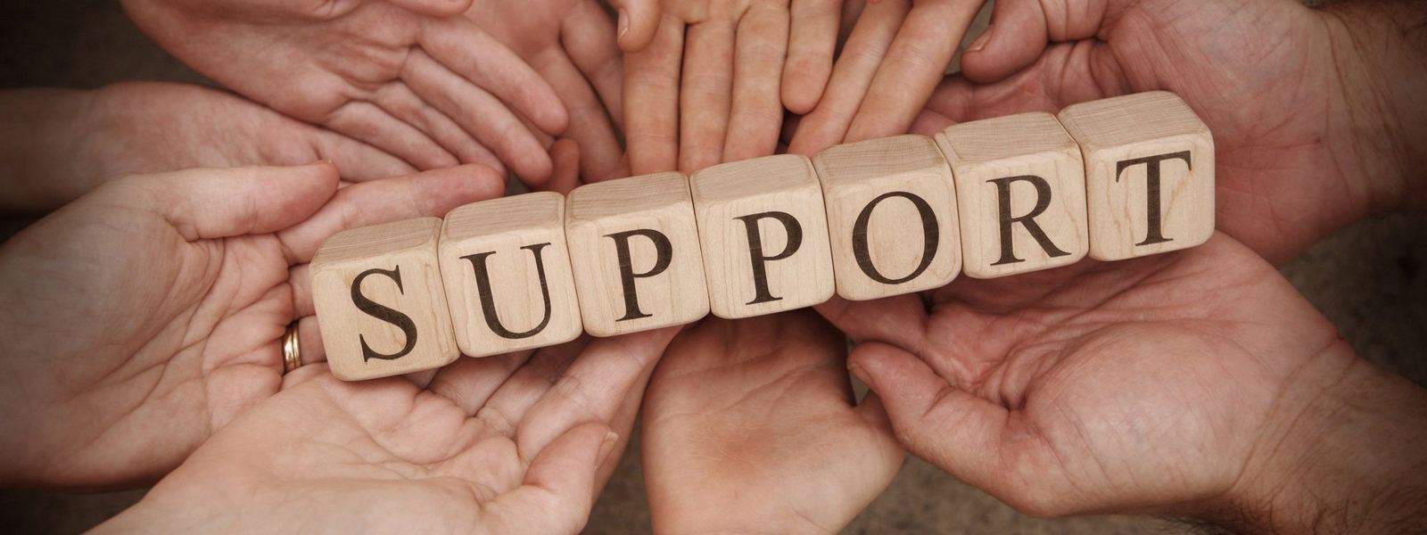 several hands holding blocks that spell support